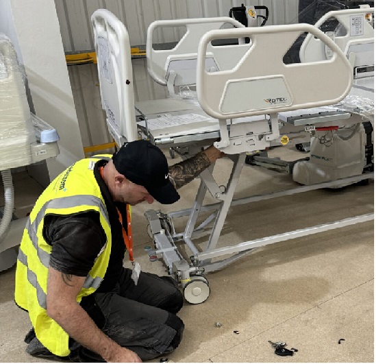 technician performing routine maintenance on a hospital bed