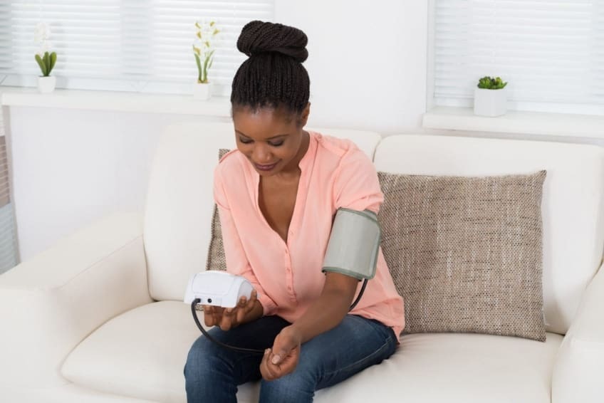 family member using a digital blood pressure monitor one of the ensential medical devices at home