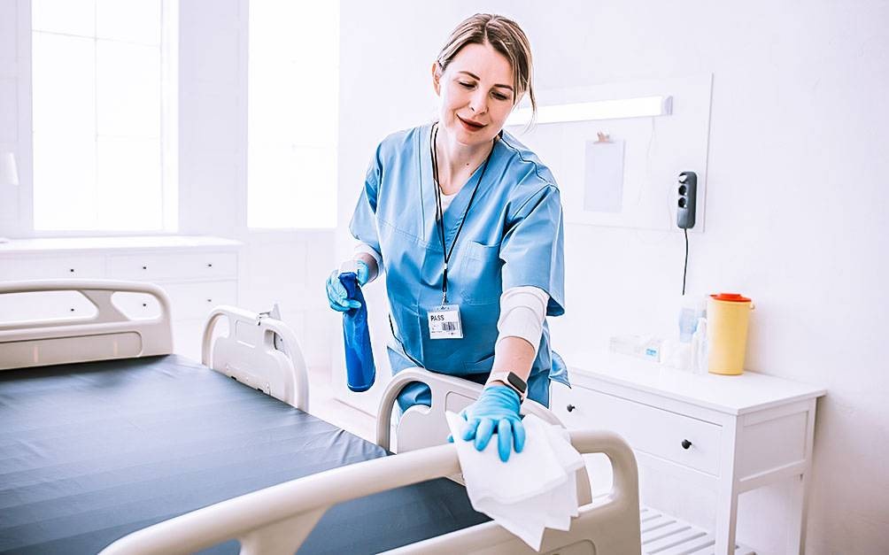 A hospital technician inspecting or servicing medical equipment in a clinical setting.