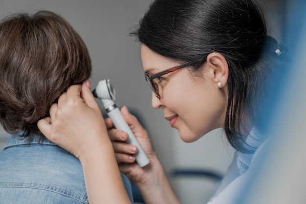 Close-up of doctor examining ear with otoscope