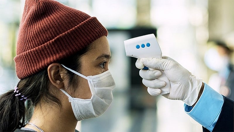Clinic staff using infrared thermometer for screening.