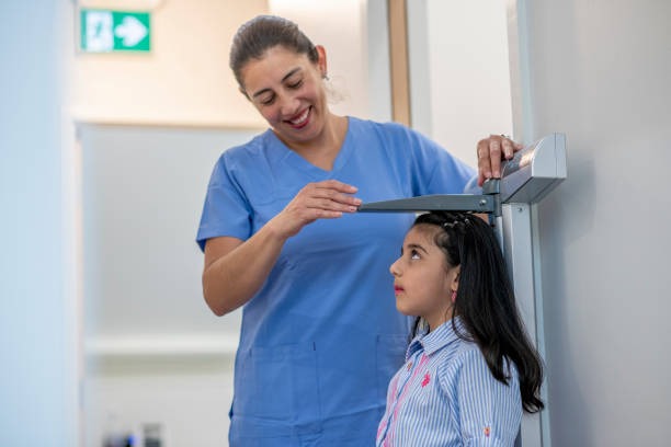  Nurse measuring height and weight of a child in clinic.